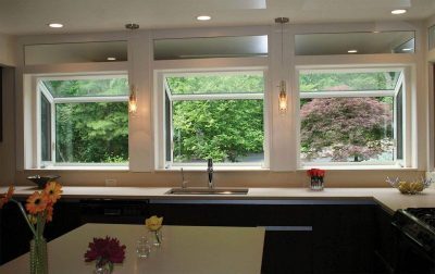 Three identical garden windows lining a kitchen wall and overlooking a group of trees
